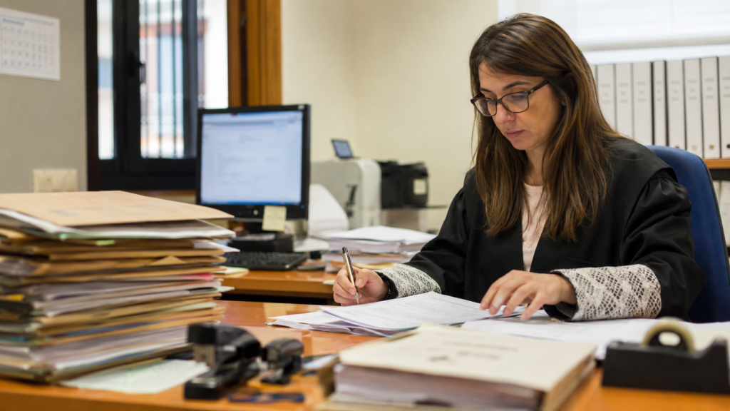 Funcionaria revisando expedientes judiciales en una oficina de Justicia