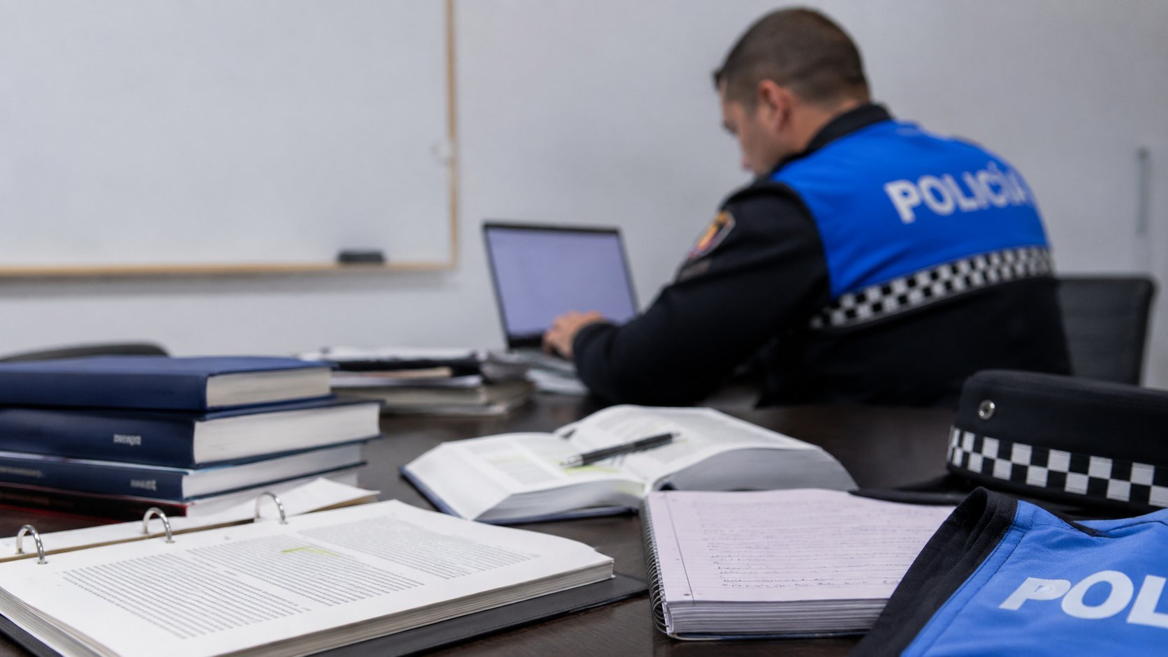 Dos agentes de Policía Local de Castilla y León frente a un ayuntamiento con las banderas autonómica, española y europea